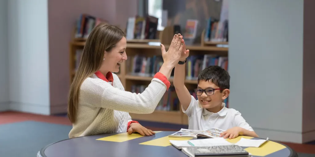 A tutor and student giving each other a high-five
