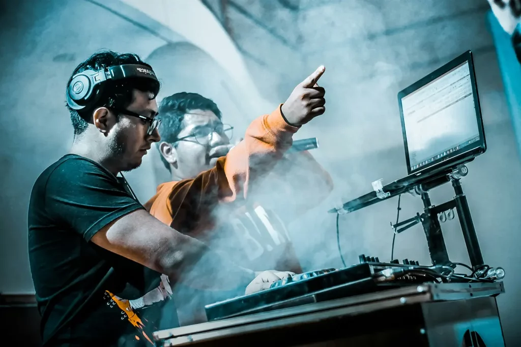A DJ and an emcee performing at a turntable in a room with a smoke machine.