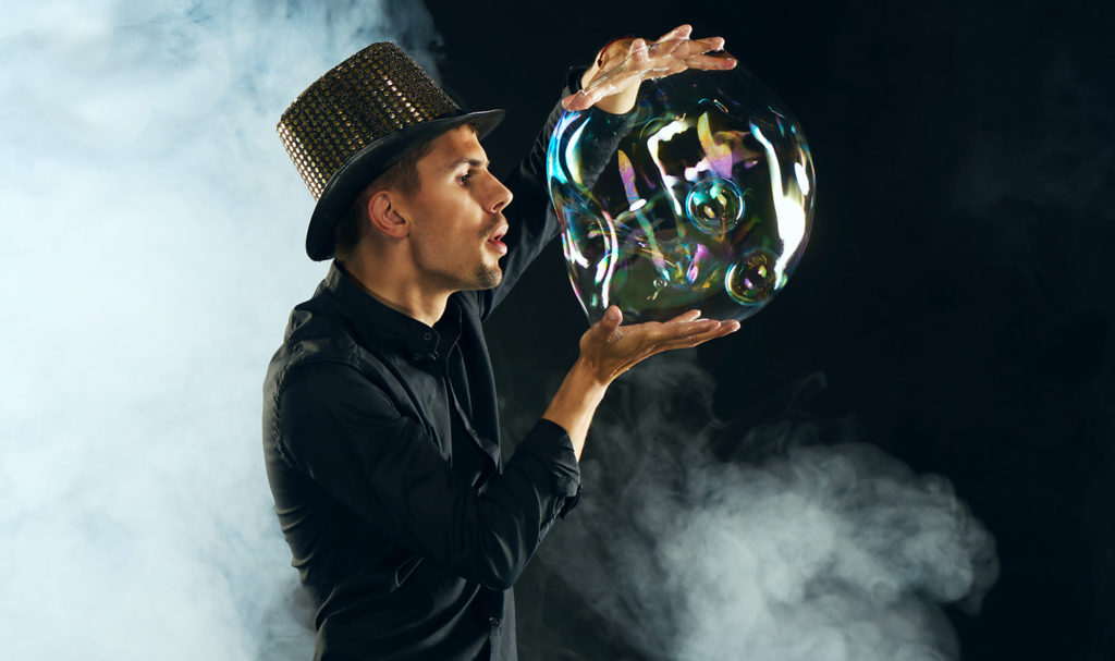 A magician is performing a trick with a giant bubble after purchasing magicians insurance.