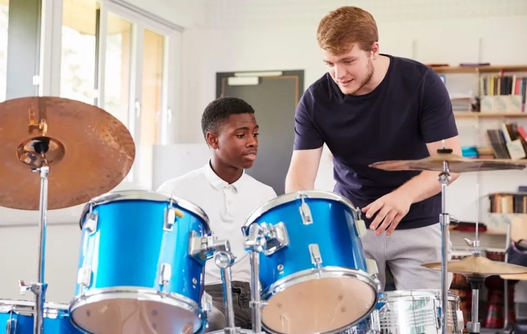 Private music teacher with student learning by a drum set.