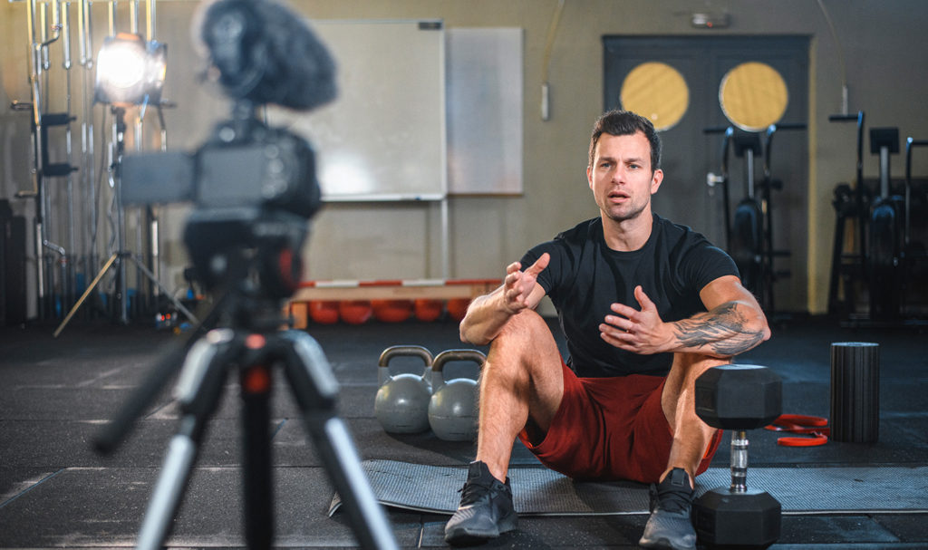 A personal trainer films himself in a private studio for his online training videos.