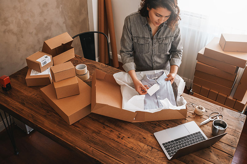 A woman is working on shipping an order for her online business in her home.