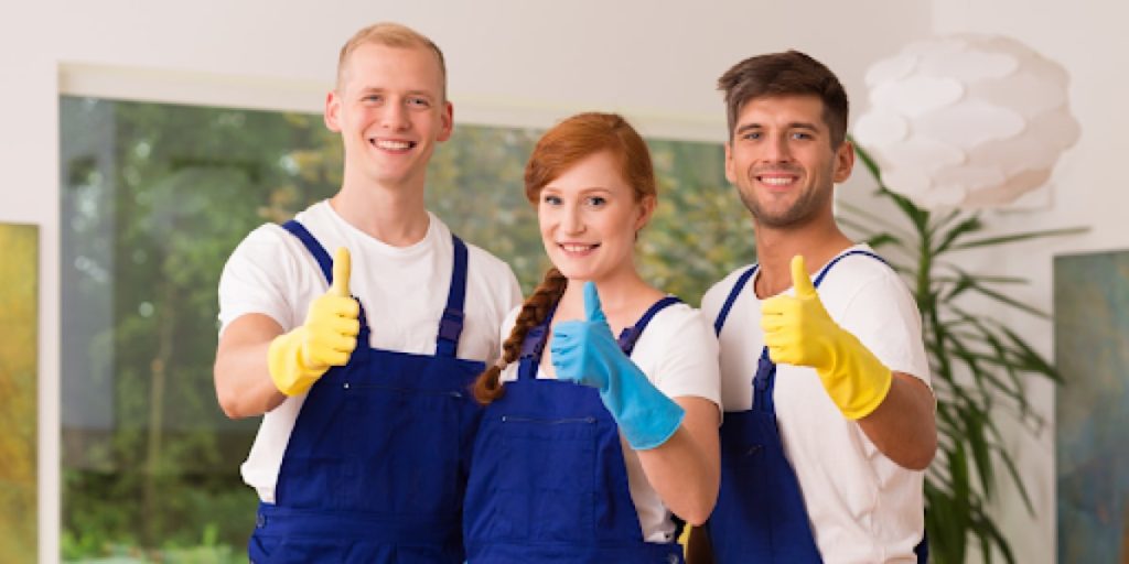 people in cleaning uniforms smiling and thumbs-up-ing the camera