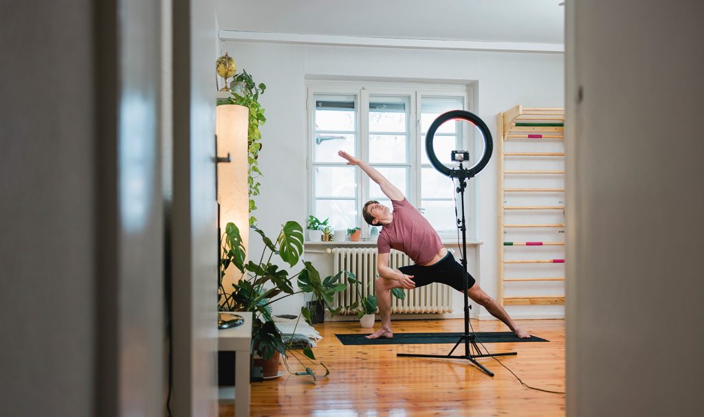 An online yoga teacher films a pose from their home workout studio for their online personal training packages.