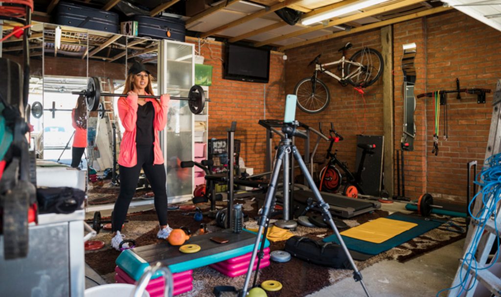 An online personal trainer films herself working out in her garage where she has converted some of the space for hosting her live training sessions.