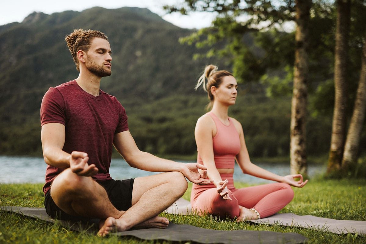 Yoga instructors meditate outdoors.