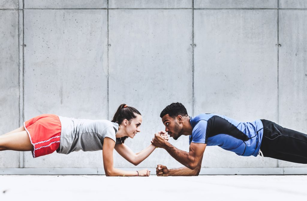 A personal trainer is insured with fitness instructor insurance and does planks with a client.