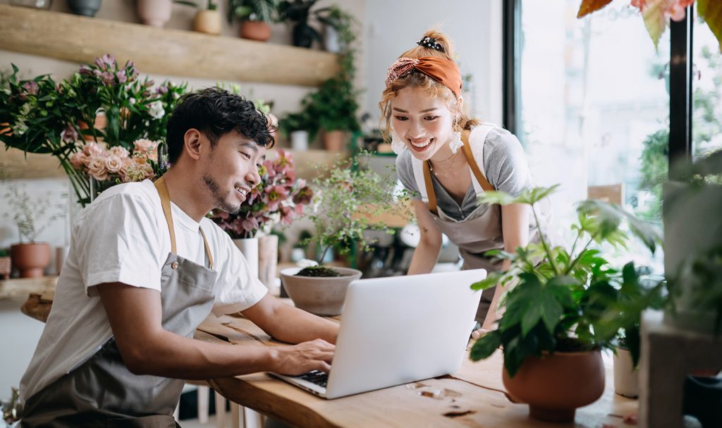 Two small business employees are reviewing their tax software together so they can keep their finances in order at their locally run floral shop.