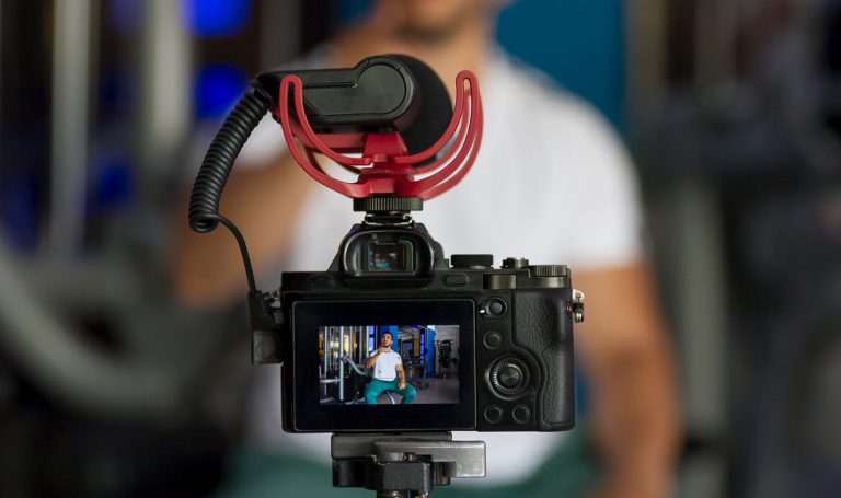 A close up shot of an trainer filming himself on his camera for his online workout series.