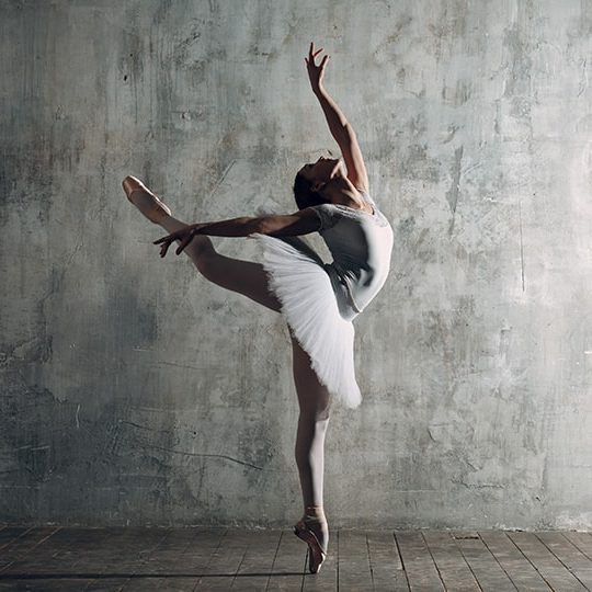 A dancer rehearses in a moody room.