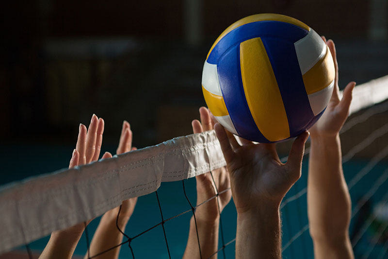 A volleyball player's hands reach up for a spike.