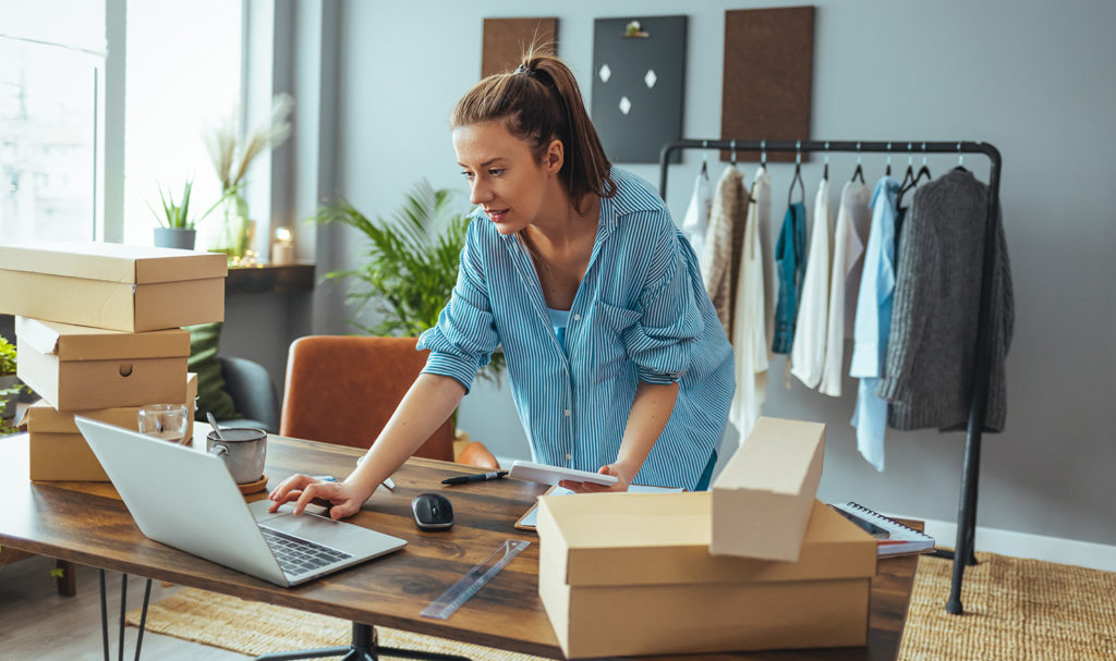 A young woman is preparing packages in her home as she is dropshipping products from her online Amazon store to customers. Her product liability insurance allows her to have coverage for products in shipment.