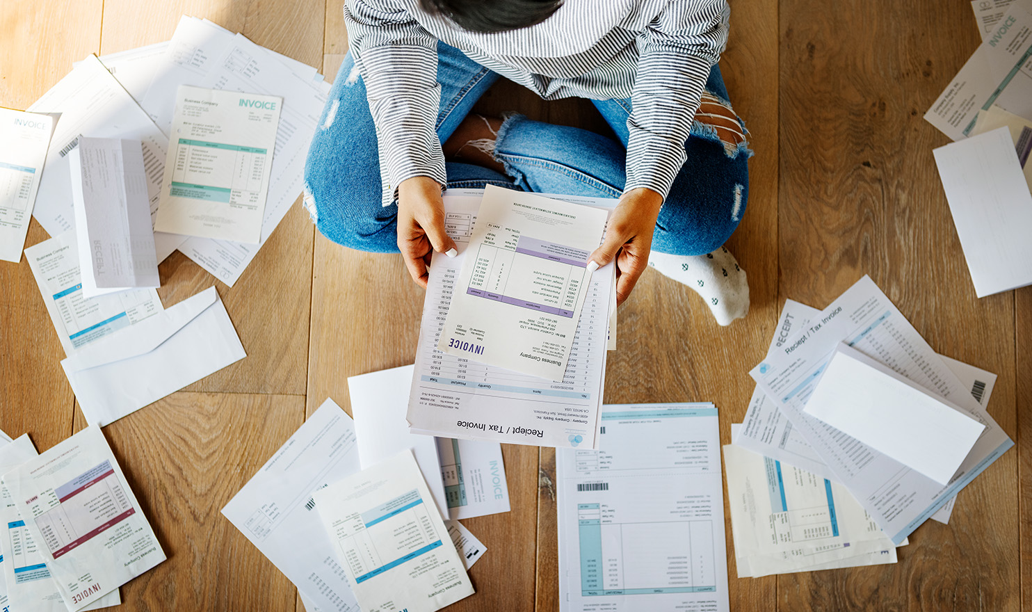 A person is sitting on the floor surrounded by receipts and business documents to use for a quote for product liability insurance.