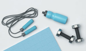 A blue yoga mat, weights, a jump rope, and a blue reusable plastic water bottle lay on a white background.