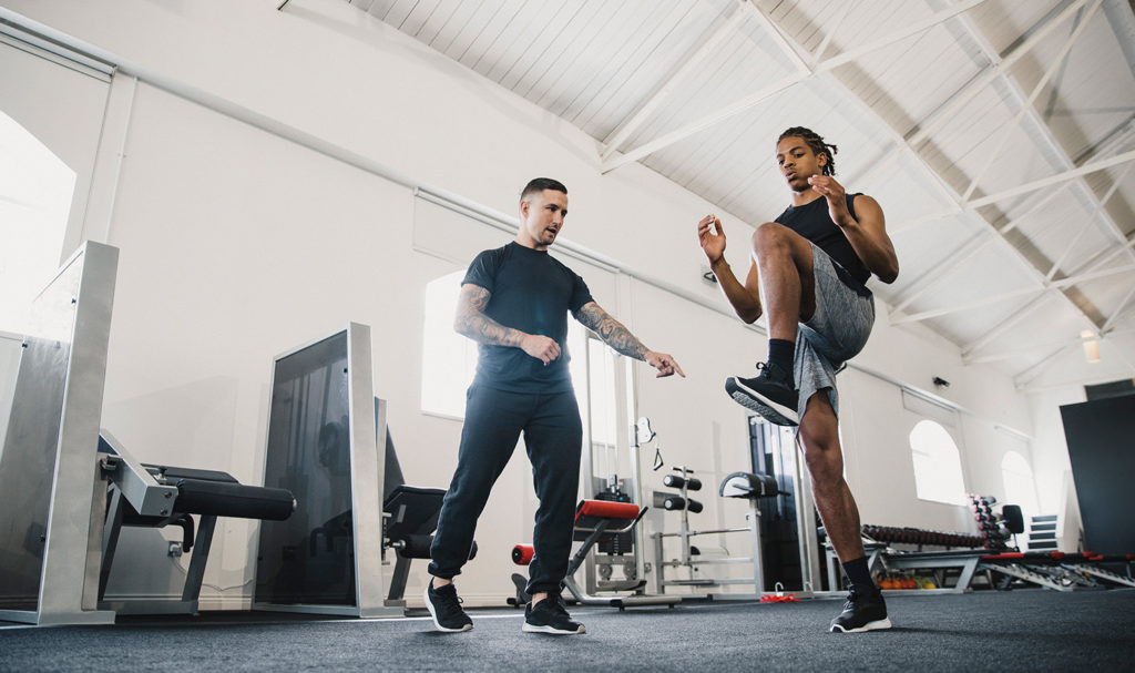 A personal trainer is guiding his client through a high knees workout set to help him improve his strength and resistance.