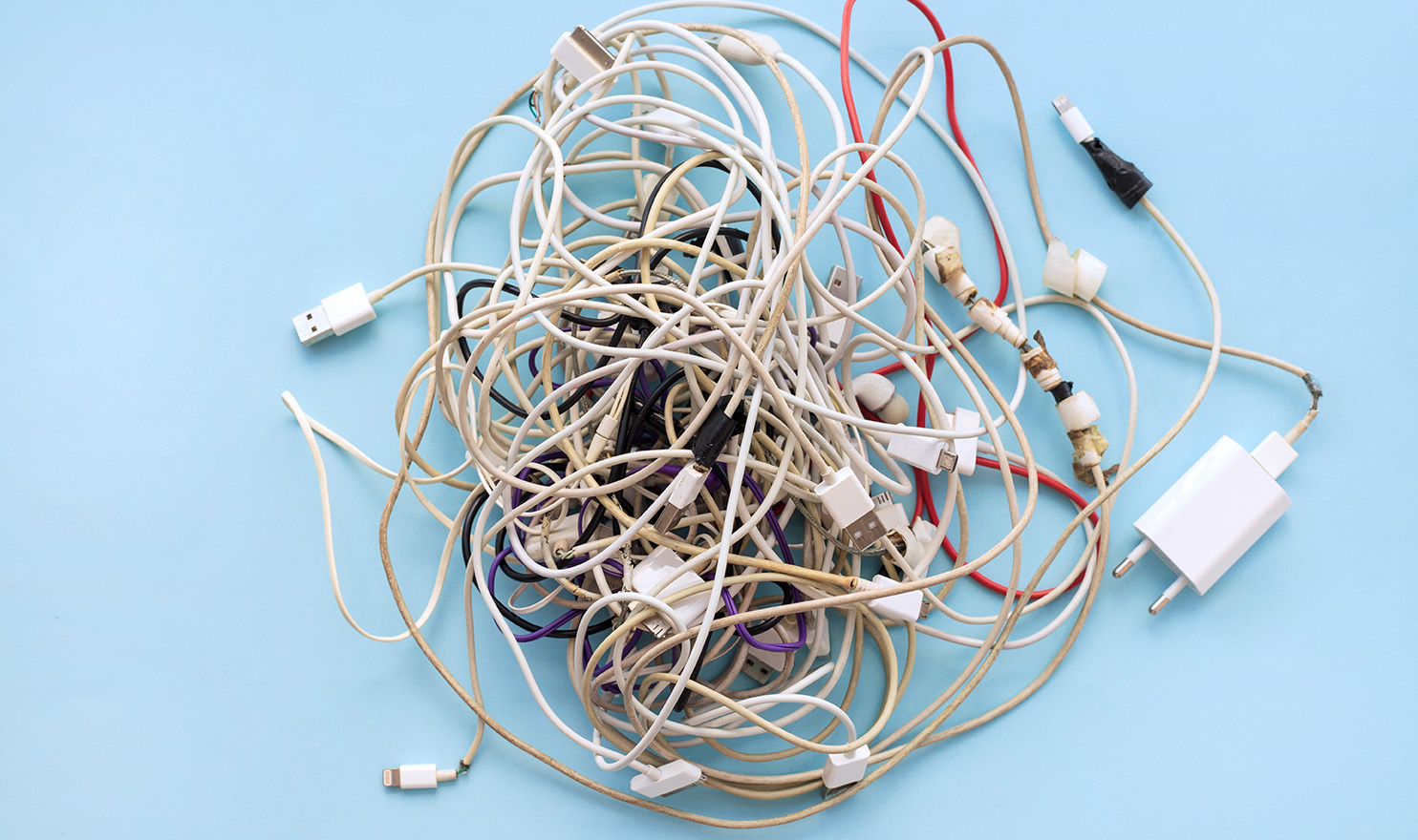 A pile of used and broken chords sits tangled up in a bundle on a blue background.