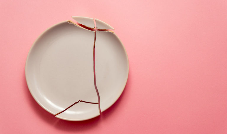 A broken clay plate sits on a pink background. This kind of damage may be covered by product liability insurance.