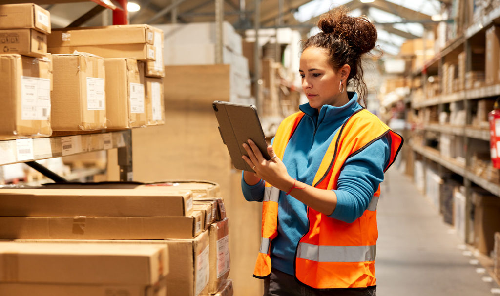 A woman in a warehouse is taking inventory for her product liability insurance policy.
