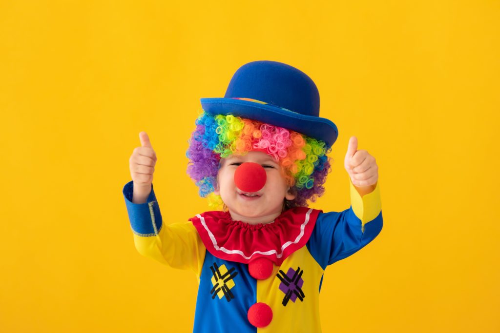 funny kid clown playing against yellow background