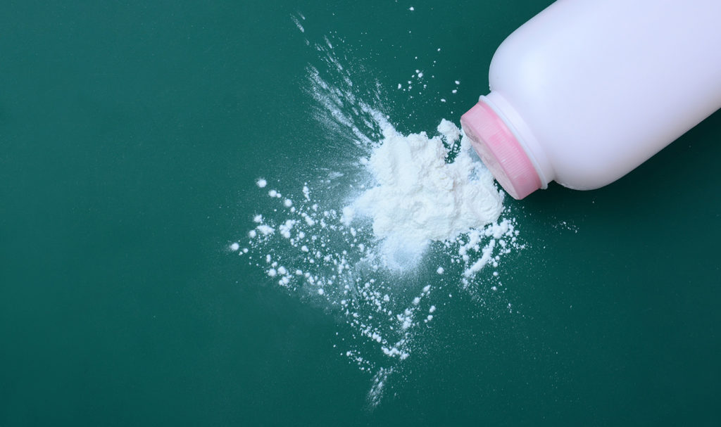 A bottle of baby powder spilled out onto a green background.