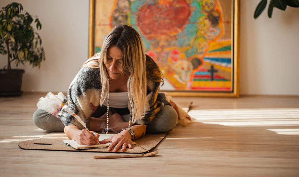 A woman lays on her yoga mat as she takes notes during her yoga teacher certification course.