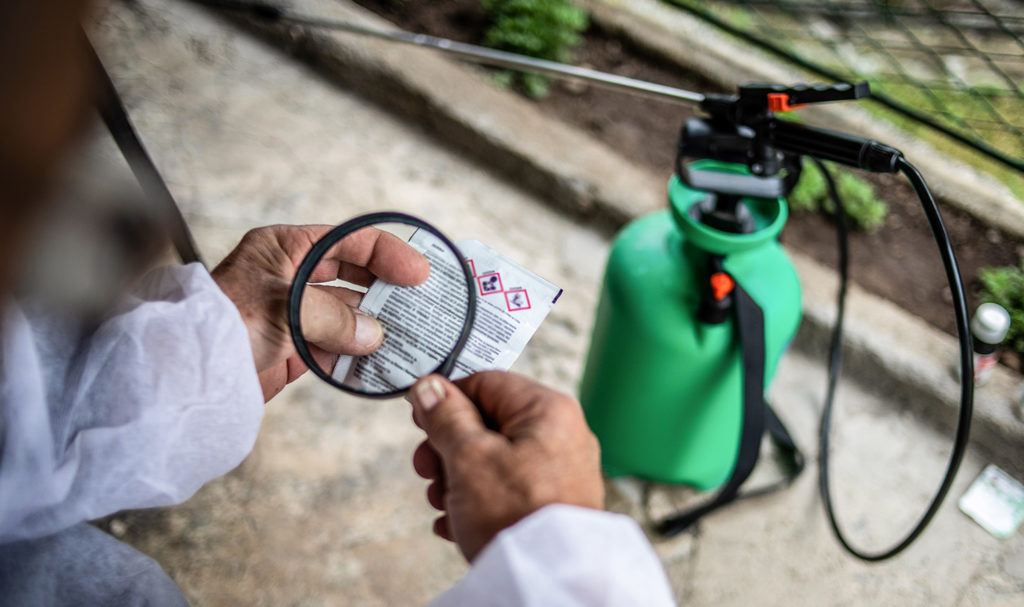 A person is reading the label and warnings for a bottle of weed killer. Failing to properly label a product can lead to lawsuits, but product liability insurance can help pay for these costs.