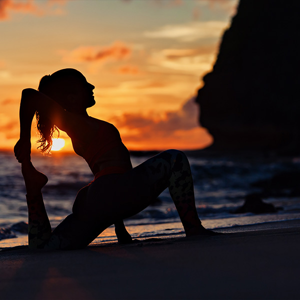 A yoga instructor does yoga on the beach.