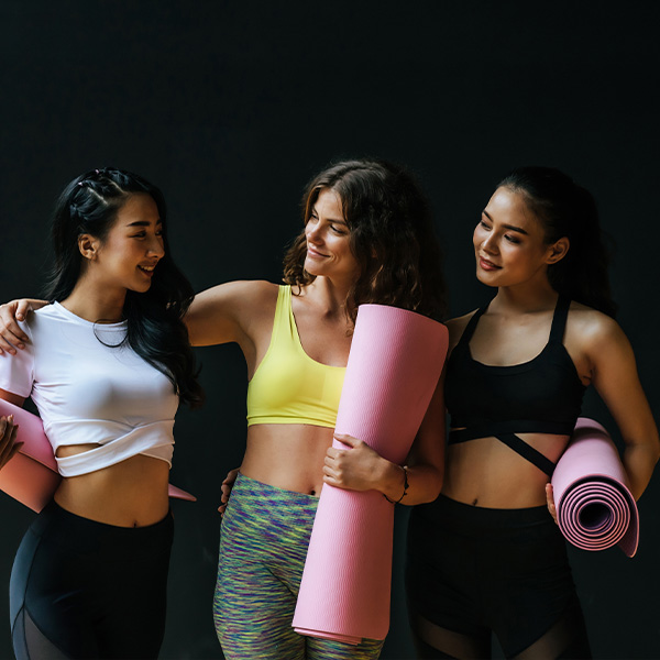 Friends smile together with yoga mats.