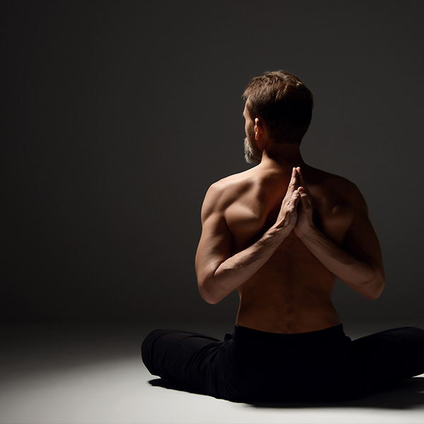 A yoga instructor holds his hands behind his back.