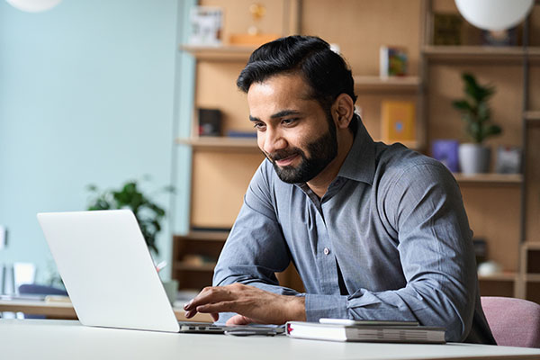 A small business owner working on a laptop in his home office as he reviews his business and product liability insurance options.