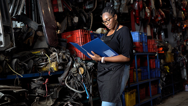 A business owner looks at paperwork in a binder on a shop floor.