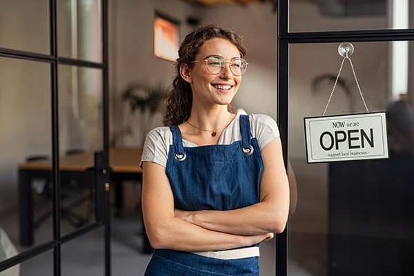 A proud business owner is ready with an open store.