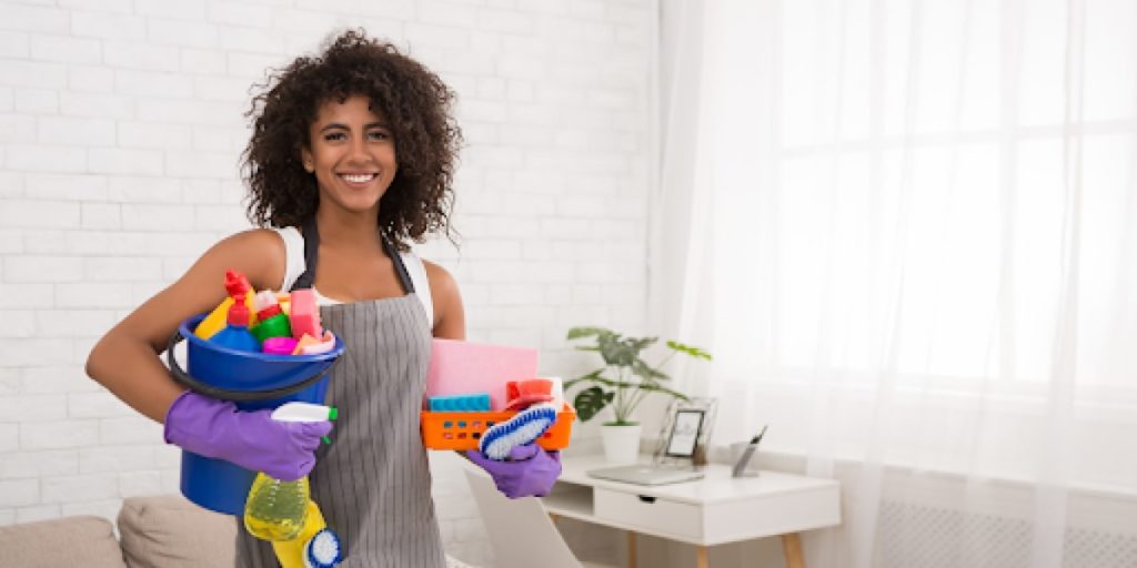 woman smiling holding cleaning supplies