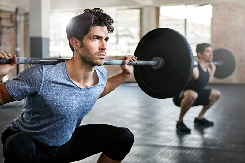 A Personal trainer squats a barbell.