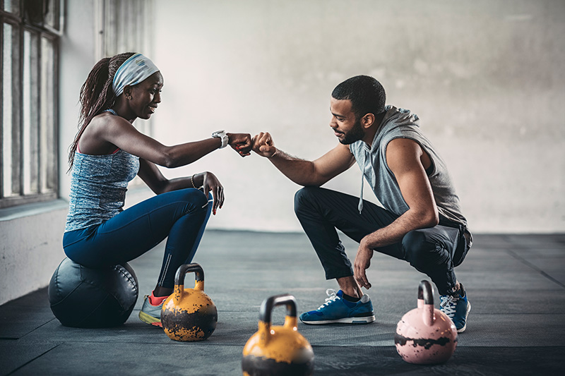 a trainer fist bumps with a client in the gym