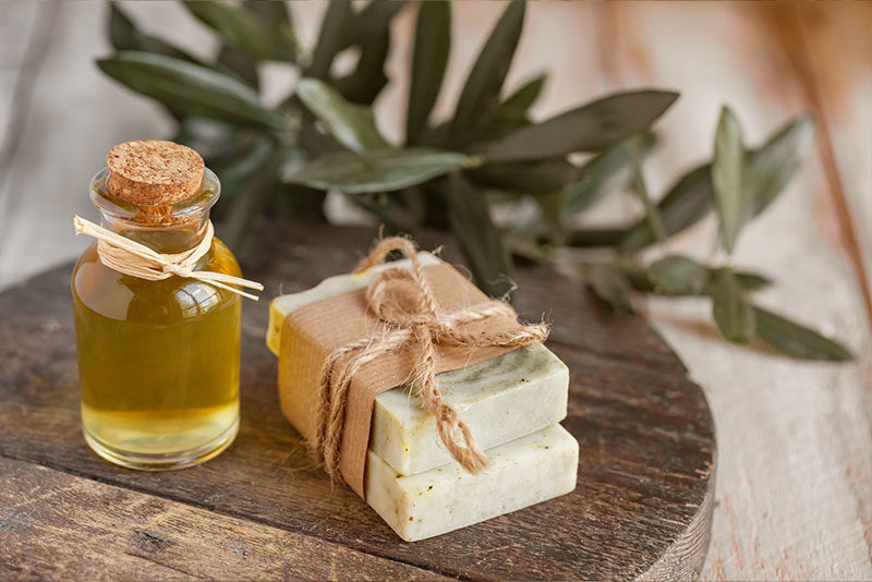 Beautiful handcrafted soap sits on a wooden table with a bottle of handmade cosmetic oil.