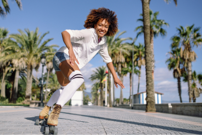 woman on skates cruising down a palm tree lined sidewalk