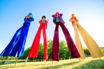 group of 4 brightly dressed people on stilts