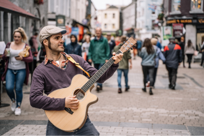 man in street performing with guitar