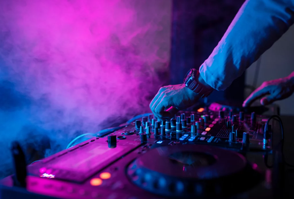 DJ plays at an event with colorful lighting