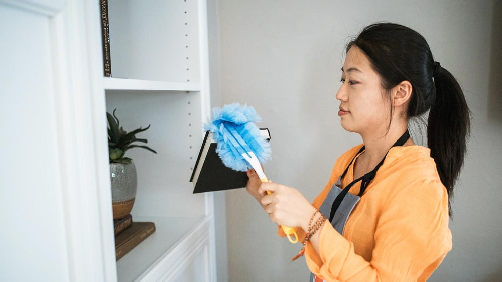 woman dusting and cleaning shelves