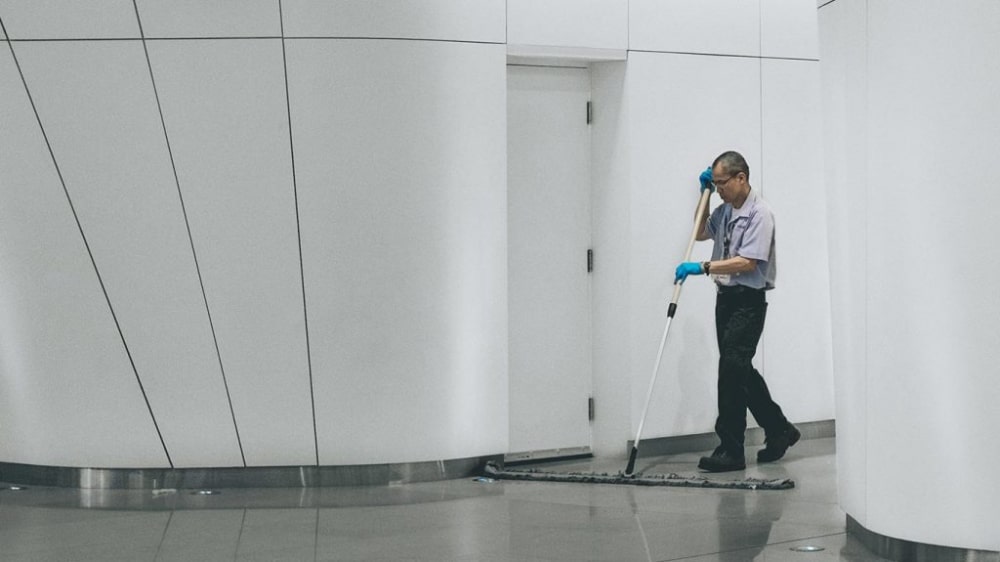 janitor in corporate hallway cleaning