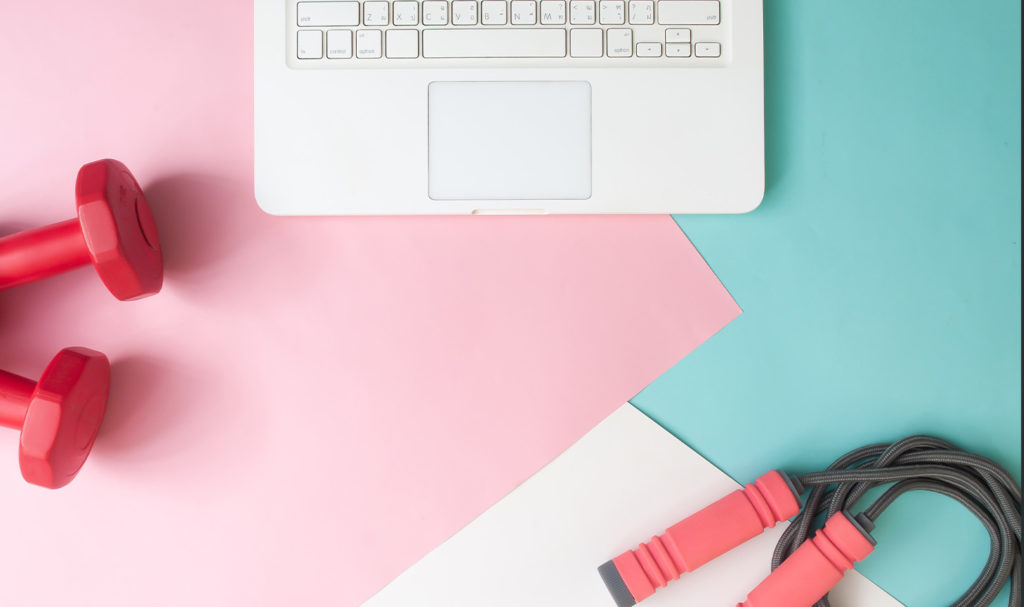 A laptop, jumprope, and dumbells sit on fun, pastel colors. Learning how to get personal training clients can help you expand your business and find the clients that best match your training styles.