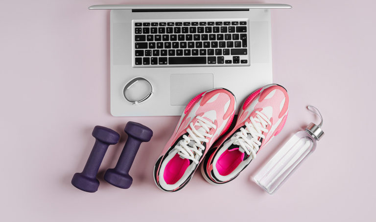 An image of a laptop with a water bottles, pink running shoes, and weights are sitting on a pink background. Personal trainer marketing can help you take your business to the next level!