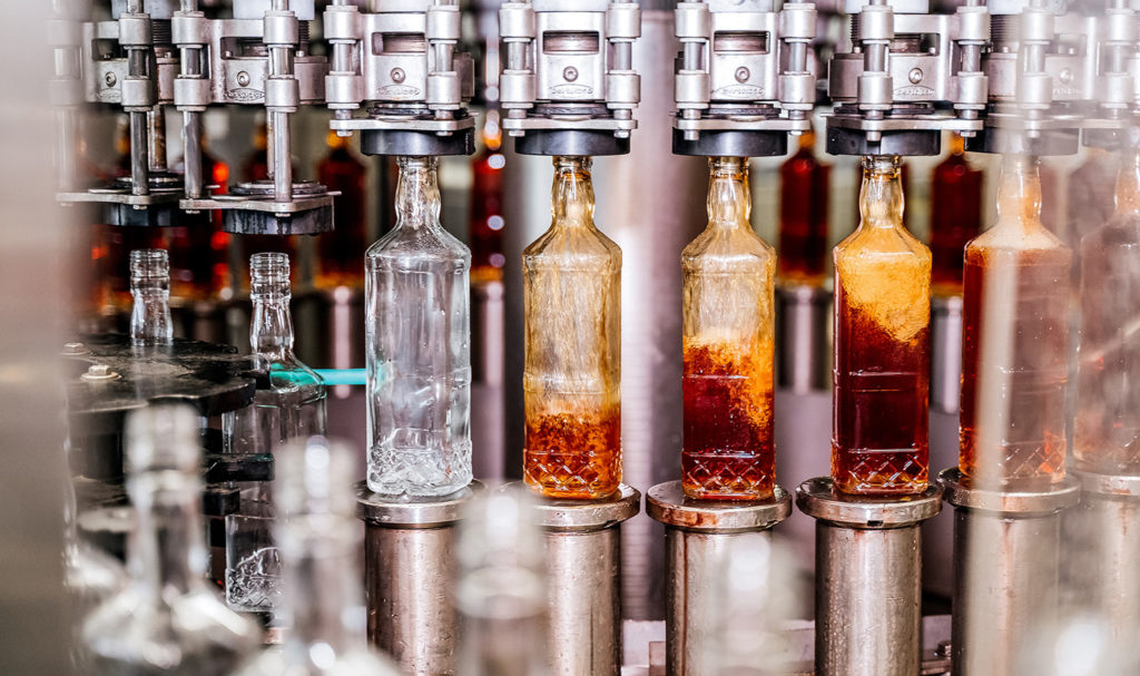 A conveyor belt is automatically filling up bottles with a liquid before it is finished with the packaging process and ready to be shipped to stores. This business would benefit from having a product liability insurance food policy.
