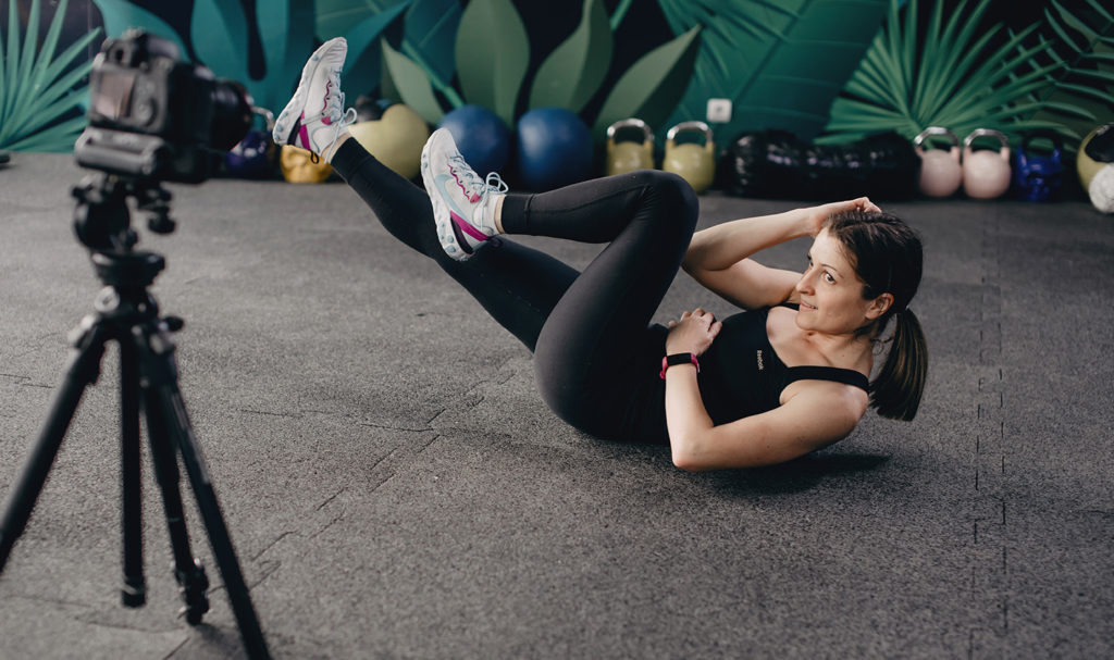 A woman does crunch exercises in front of a camera.