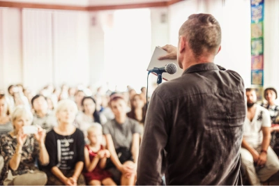 poet or storyteller with notebook in front of crowd