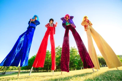 group of 4 brightly dressed people on stilts