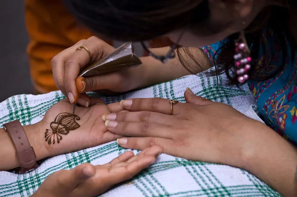 Henna artist applying design to palm of hand