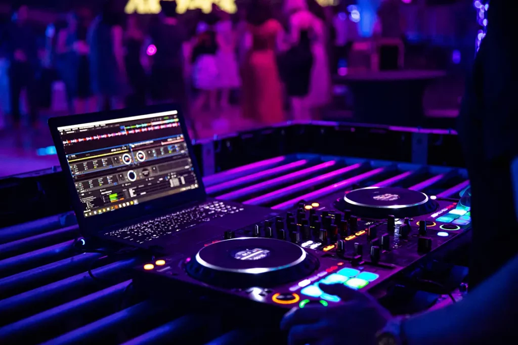 DJ working an event with their equipment set up showing a laptop and turntable